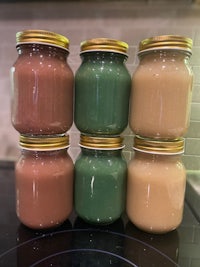 five jars of different colored liquids sitting on top of a stove