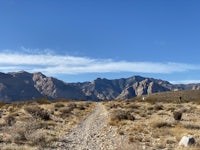 a dirt road in the desert with mountains in the background