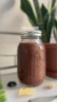 a jar of chocolate sauce on a counter next to a plant